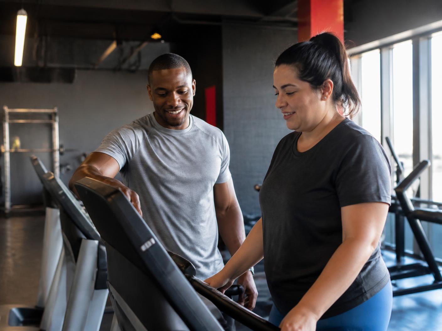 Personal trainer guiding a beginner through a treadmill workout