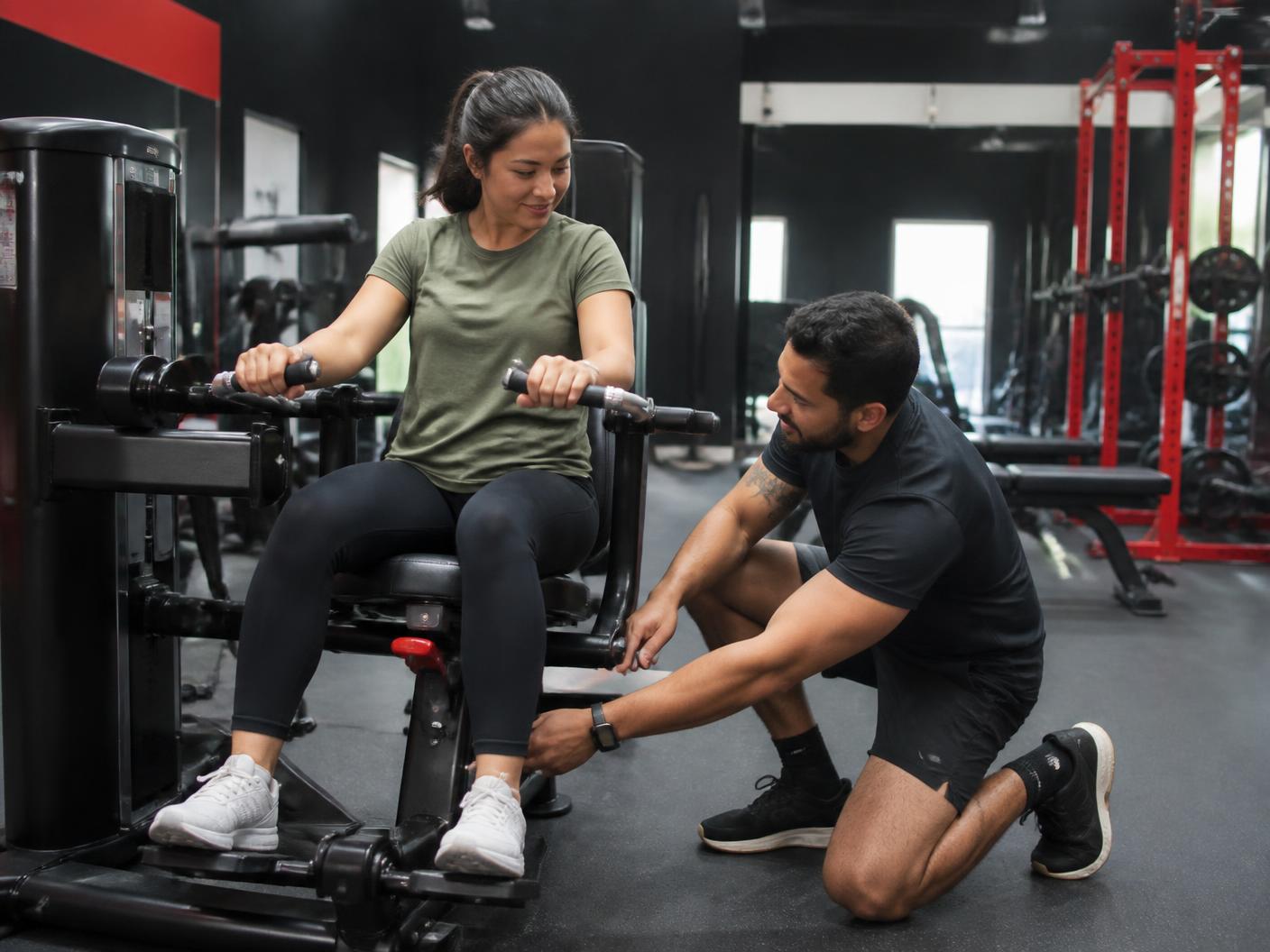 Personal trainer helping a beginner set up a strength machine