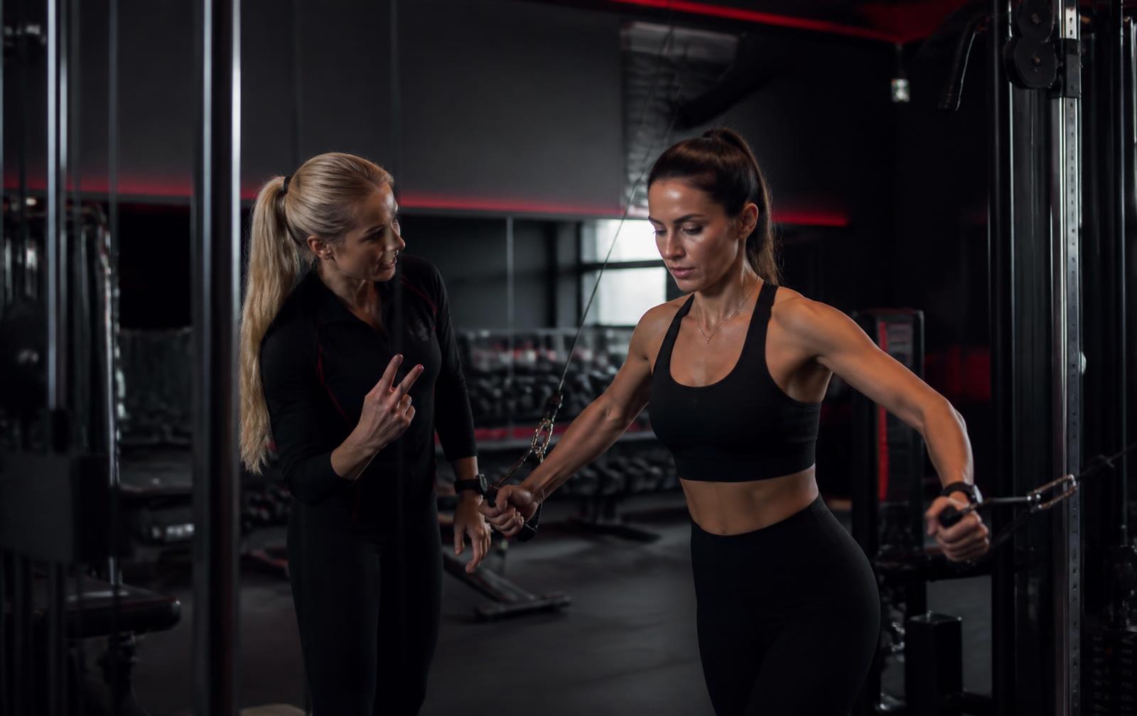 Personal trainer coaching a client on the cable machine