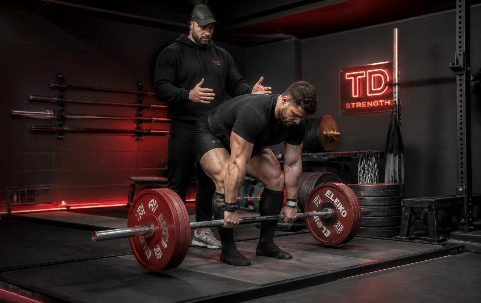 Coach spotting a lifter setting up a heavy deadlift